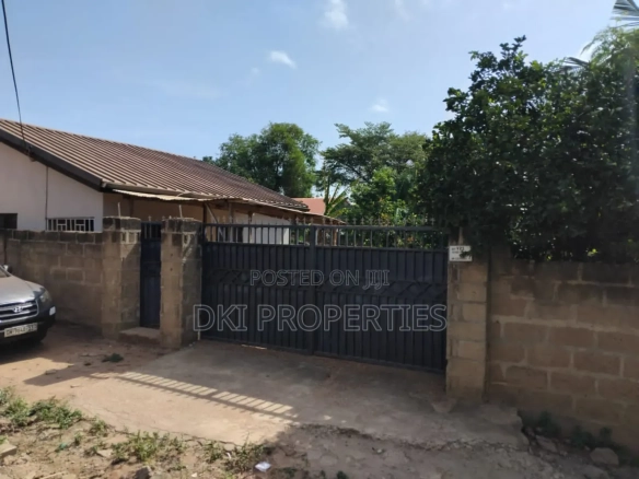 Exterior view of a fairly used 2-bedroom detached house within a walled and gated compound on a large plot of land in Amrahia, Adenta.