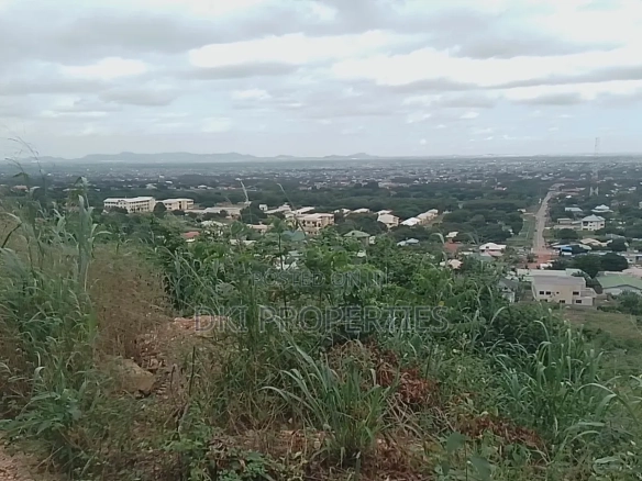 Photo of a cleared residential plot on a hill overlooking the town of Apirade in the Akuapim North District.