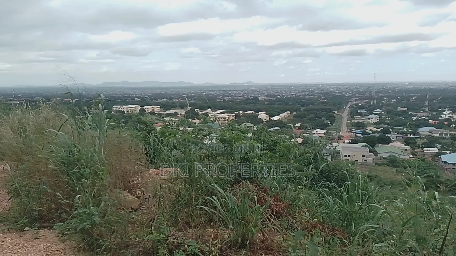 Photo of a cleared residential plot on a hill overlooking the town of Apirade in the Akuapim North District.