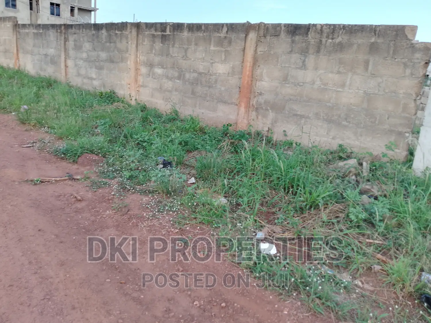 Photo of a fenced, cleared land plot on a tiled road in the North Legon area of Accra, ready for mixed-use development.