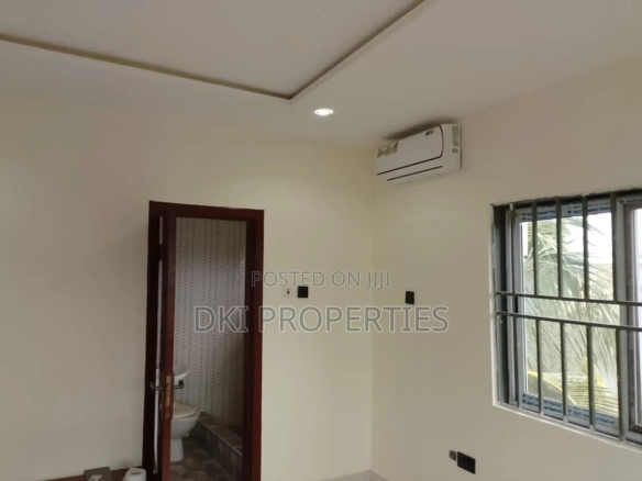 Interior view of a neat and spacious executive 2-bedroom apartment in Oyarifa, showing the fitted kitchen cabinets, tiled floor, and a hint of the air conditioning unit.