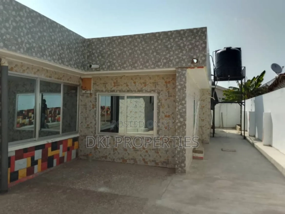 Exterior view of a large, fairly used 15-bedroom house on a plot in Kwashieman, showing the fenced and gated compound suitable for commercial or institutional use.