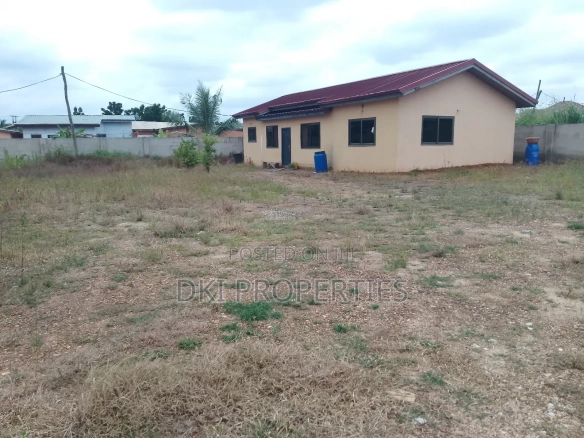 Exterior view of a newly-built, unfurnished 2-bedroom detached house in Oyibi, emphasizing the vast, empty compound space around it, highlighting the two plots of land.