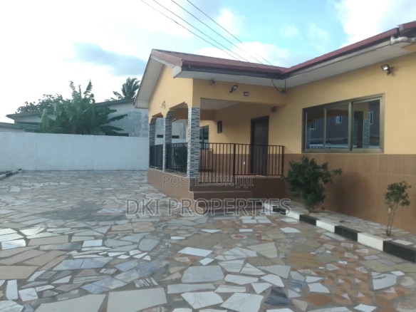 Exterior view of a fairly used 3-bedroom detached house in Adenta New Legon, showcasing the very spacious compound suitable for parking up to $\text{10}$ cars and indicating space for potential future development.